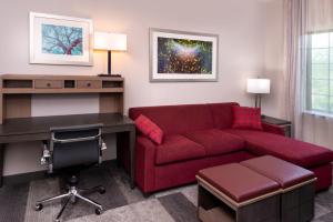 a living room with a red couch and a desk at Staybridge Suites - Lake Charles, an IHG Hotel in Lake Charles