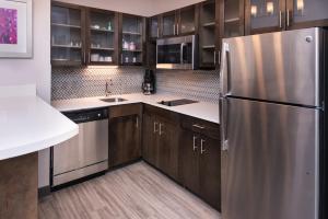 a kitchen with wooden cabinets and a stainless steel refrigerator at Staybridge Suites - Lake Charles, an IHG Hotel in Lake Charles