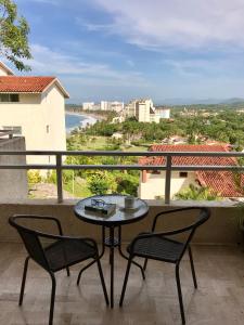d'une table et de deux chaises sur un balcon avec vue. dans l'établissement Hotel Pacifica Departamento 2220, à Ixtapa