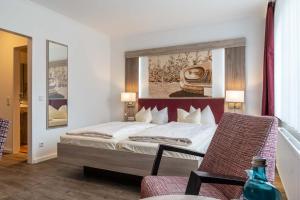 a bedroom with a bed with a painting on the wall at Frommanns Landhotel in Buchholz in der Nordheide