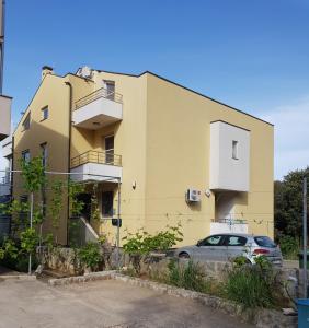 un bâtiment jaune avec une voiture garée devant lui dans l'établissement Sun studio apartman, à Zadar