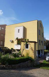 un bâtiment jaune à côté d'un parking dans l'établissement Sun studio apartman, à Zadar