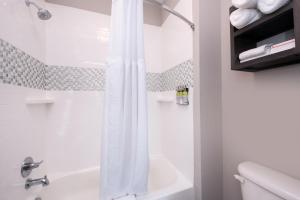Staybridge Suites - Lake Charles, an IHG Hotel في ليك تشارلز: حمام أبيض مع دش وحوض استحمام أبيض