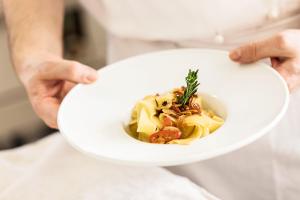 a person holding a white plate of food at Landgasthof Kreuz - Businessaufenthalt mit Wohlfühlgarantie in Kappel bei Olten