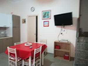 a dining room with a red table and a television at Casa vacanze Scilla in Scilla
