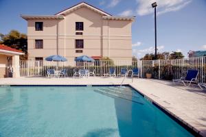 una piscina frente a un edificio con sillas y sombrillas en Extended Stay America Suites - San Jose - Edenvale - South, en San José