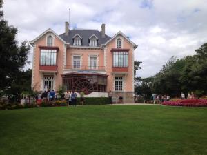 ein großes rosafarbenes Haus mit Leuten, die davor stehen in der Unterkunft La Victoire in Granville