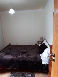 un letto con piumone nero in una camera da letto di Casa Cely a Iquique