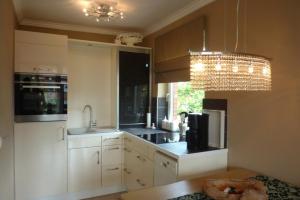 a kitchen with white cabinets and a chandelier at "Stine" in Westerland