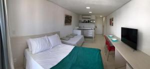 a small room with a bed and a flat screen tv at Laguna Beach Flat in Porto De Galinhas