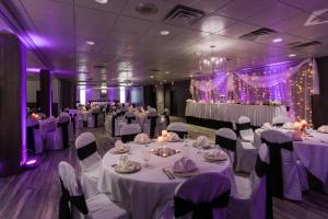 un salón de banquetes con mesas y sillas blancas e iluminación púrpura en Harbor Shores on Lake Geneva, en Lake Geneva