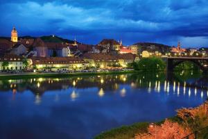 a city with a bridge over a river at night at Sobe- Rooms - Apartments - Free parking! in Maribor