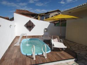 una pequeña piscina en una terraza con una silla y una sombrilla en Holiday House With Pool, en Cabo Frío