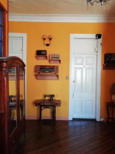 Habitación con puerta blanca y mesa de madera. en Hostal Dinamarca, en Valparaíso