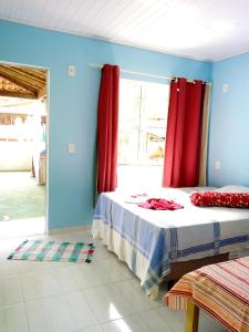 sypialnia z łóżkiem z czerwonymi zasłonami i oknem w obiekcie Nena's Suítes w mieście Praia de Araçatiba