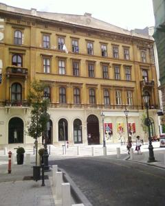 a large yellow building with people walking in front of it at City Center Apartment in Budapest