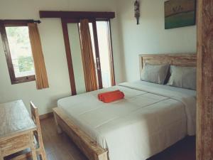 a bedroom with a white bed with a red box on it at Purnama Guesthouse in Canggu