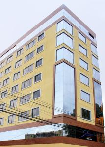 un edificio alto amarillo con muchas ventanas en Apart Hotel Selenza, en Cochabamba