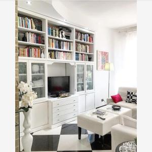 una sala de estar blanca con TV y libros en B&B Lido, en Gallipoli