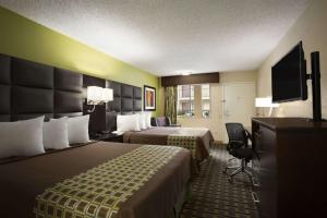 a hotel room with two beds and a flat screen tv at Days Inn by Wyndham Dallas Irving in Irving