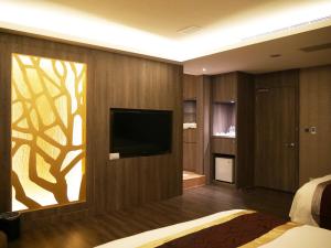 um quarto com uma televisão numa parede com um mural de árvore em Refinement Motel em Taichung