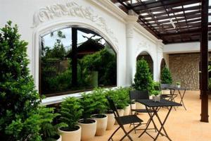 a patio area with chairs, tables, and plants at Pearl Hotel - SHA Plus in Phuket