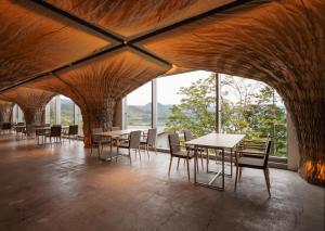 a dining room with tables and chairs and windows at WE Hotel Toya - Dusit Collection in Lake Toya