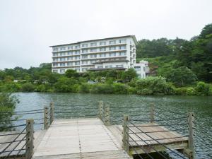 a building sitting on top of a lake with a wooden dock at Kagamigaike Hekizantei in Nihommatsu