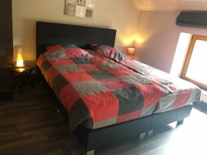 瑞都的住宿－Lesse matinal，卧室内的一张床位,配有红色和灰色的被子