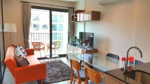 a living room with an orange chair and a kitchen at Rain Cha-am by Obbset in Cha Am