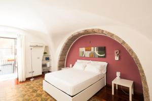 a bedroom with a white bed and a red wall at The House in Catania