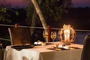 uma mesa com uma lanterna e dois copos de vinho em RiverDance Lodge em Mamono