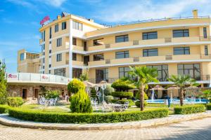 un hôtel avec des tables et des chaises devant un bâtiment dans l'établissement Hotel Airport Tirana, à Rinas