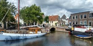 two boats docked in a canal in a city at Het Goede Leven in Harlingen