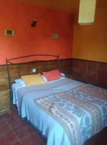 Bett in einem Zimmer mit orangefarbenen Wänden in der Unterkunft Casa Rural Las Gesillas in Arenas de San Pedro