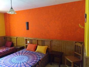 アレーナス・デ・サン・ペドロにあるCasa Rural Las Gesillasのオレンジ色の壁の客室で、ベッド2台が備わります。