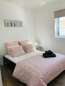 een slaapkamer met een bed met roze lakens en een raam bij Sea & Beach Apartment in Costa da Caparica