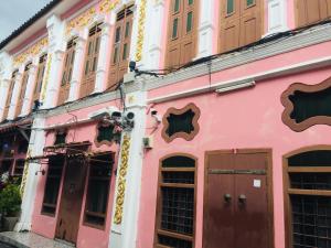 a pink building with wooden doors on a street at Phuket Sunny Hostel in Phuket Town