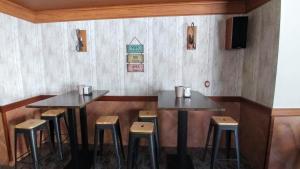 PadulにあるHostal Rural El Padulのレストラン内のテーブル2台とスツール付きの部屋