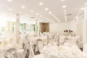 un salón de banquetes con mesas blancas y sillas blancas en Hotel Restaurant Höldrichsmühle, en Hinterbrühl