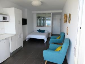 ラスパルマス・デ・グランカナリアにあるApartamento 1ª linea Las Canteras -vista mar con terraza y wifi - 307のベッド1台と青い椅子2脚が備わる客室です。