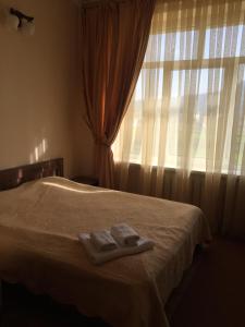 a bedroom with two towels on a bed with a window at DOLCHE VITA in Berehomet