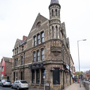 um antigo edifício de pedra com uma torre de relógio numa rua em The Glebe Hotel em Liverpool