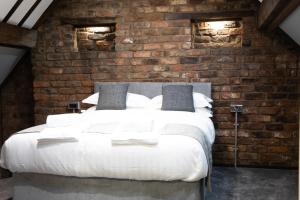 a bedroom with a large white bed in a brick wall at The Glebe Hotel in Liverpool