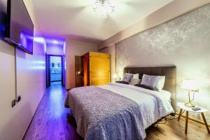 a bedroom with a large bed with purple lighting at Apartment Chic by Landev in Braşov