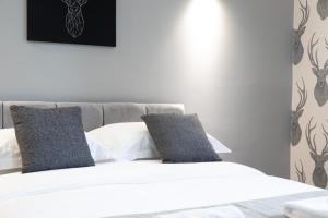 a bedroom with a bed with white sheets and gray pillows at The Glebe Hotel in Liverpool