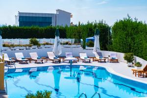 a swimming pool with lounge chairs and umbrellas on a building at Hotel Airport Tirana in Rinas