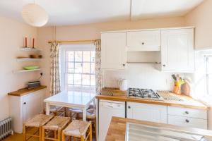 eine Küche mit weißen Schränken und einem Tisch mit Stühlen in der Unterkunft 5 Coastguard Cottages in Aldeburgh