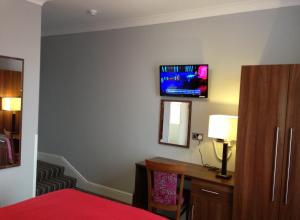 a bedroom with a television and a bed at Ely House Hotel in Wolverhampton