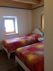 a room with two beds and a window in it at B&B Contrade Alte in SantʼAnna dʼAlfaedo